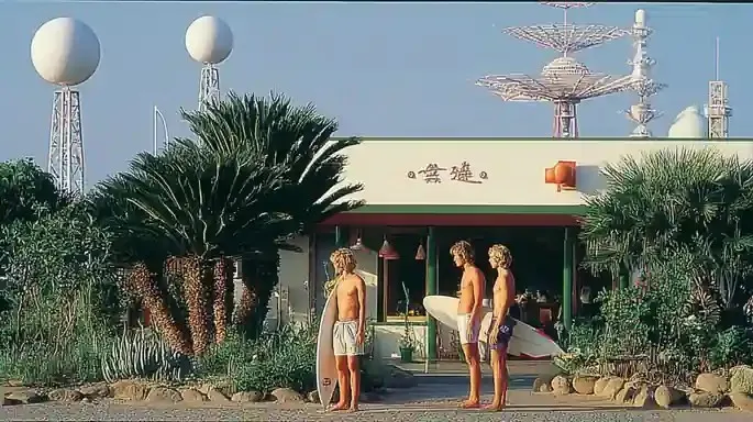 Three Surfers Waiting beside a Faded Roadside 4, a Midjourney sref remix: three surfers waiting beside a faded roadside fruit stand before dawn, sun-bleached glass satellites orbit backward through a silent film studio, surrounded by enormous houseplants, retro photo style