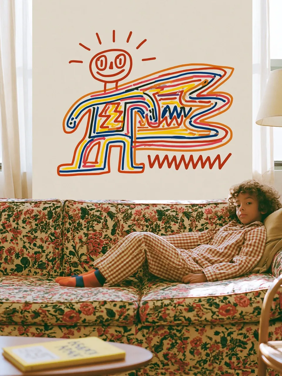 Rainbow Caped Reading Hour, a Midjourney sref remix: A crayon-scrawled caped hero in rainbow strokes sits beaming beside a sunlit reader curled in checkered pajamas on a floral sofa., playful photo style