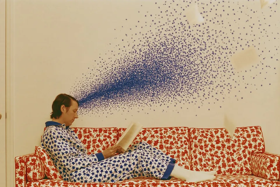 Storybook Vortex, a Midjourney sref remix: A cozily pajamaed reader curls up on a floral sofa while a gentle swirl of blue starlight and fluttering pages dances overhead in warm, dreamy light., dreamy photo style